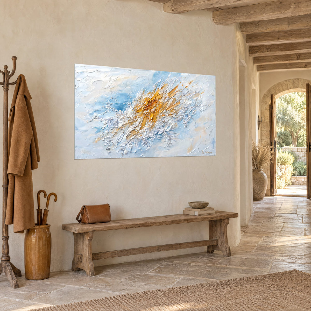 Tableau explosion ocre safran aux ramures argentées, bleu ciel et blanc crème, accroché dans une entrée de pierre voûtée et dallée