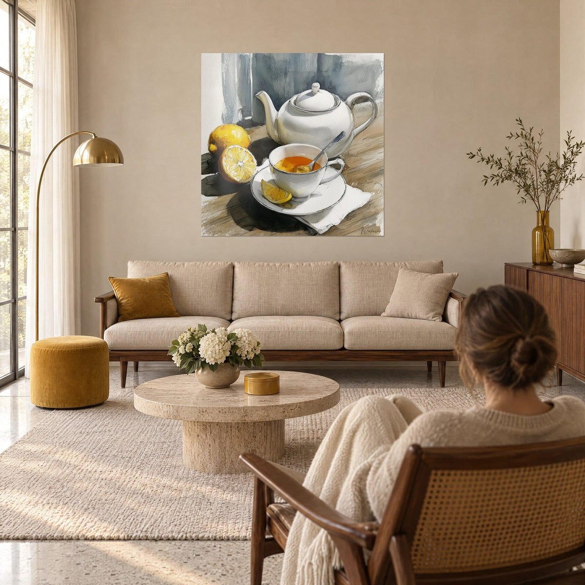 Wall art white porcelain teapot and yellow lemons, grey-blue background, a woman seen from behind, above a sofa in a bright living room