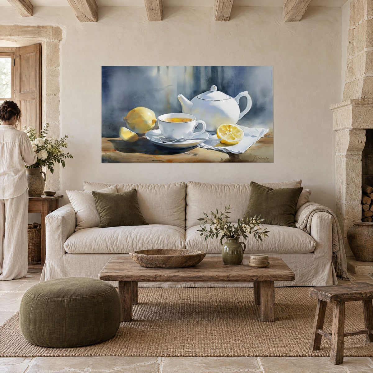 Quadro teiera in porcellana bianca, limoni gialli e tazza fumante su sfondo blu ardesia, donna di spalle, sopra un divano in un soggiorno luminoso