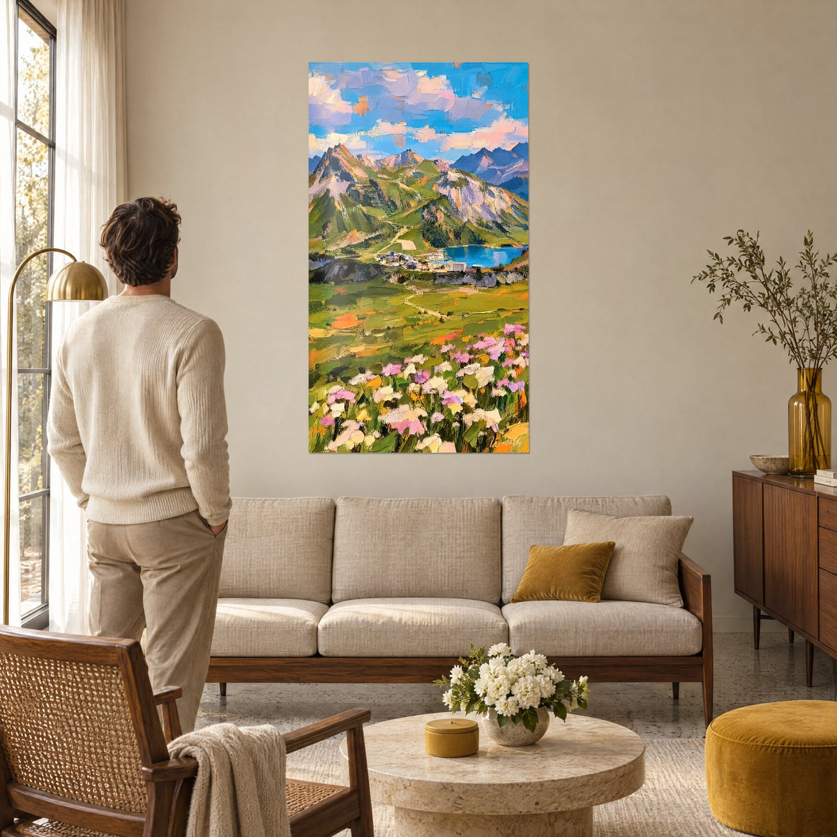 Quadro villaggio di montagna sulla riva di un lago blu, prato verde e fiori rosa, uomo di spalle, sopra un divano in un soggiorno luminoso