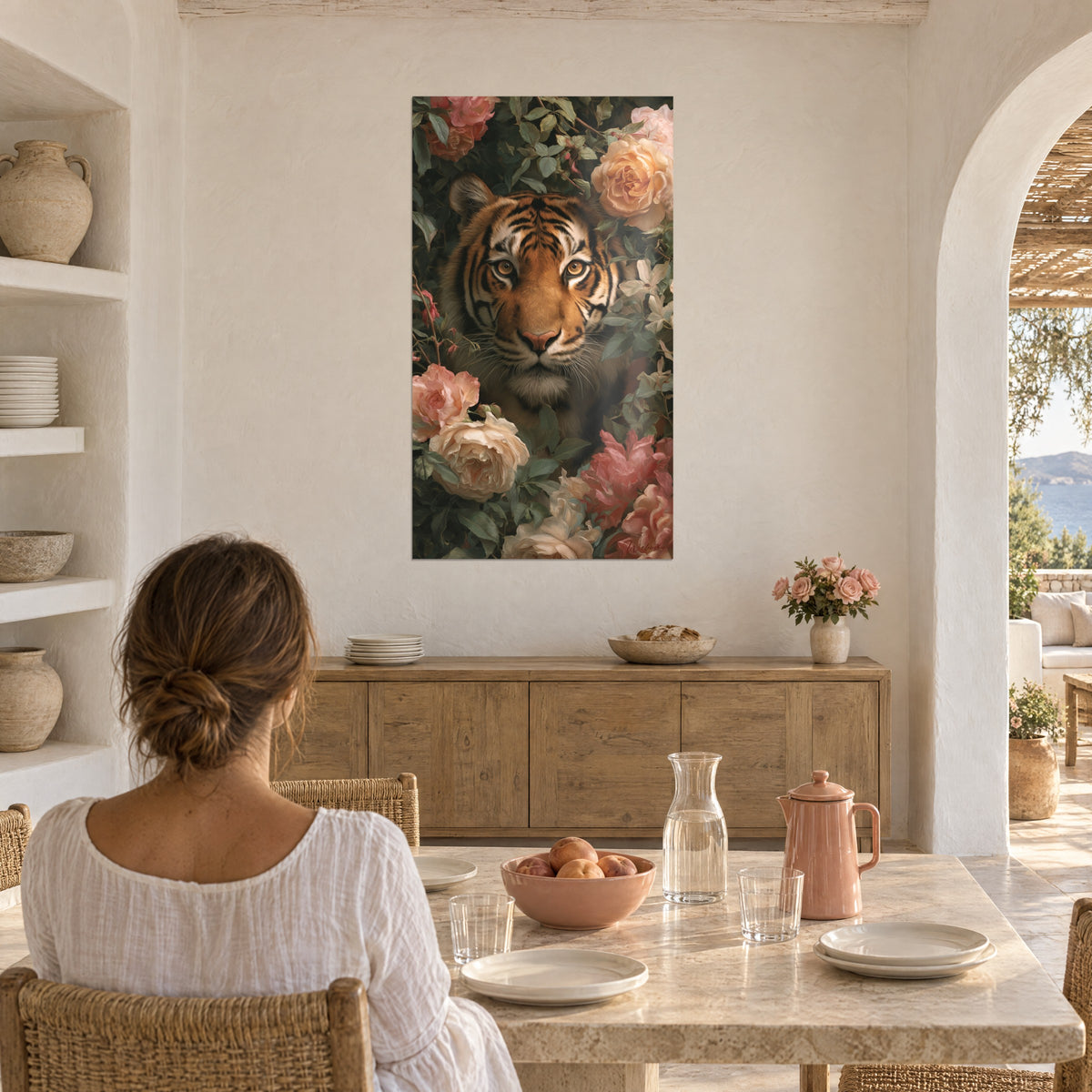 Cuadro retrato de tigre dorado rodeado de rosas pálidas y coral, pared crema, mujer de espaldas sentada bajo un arco blanco