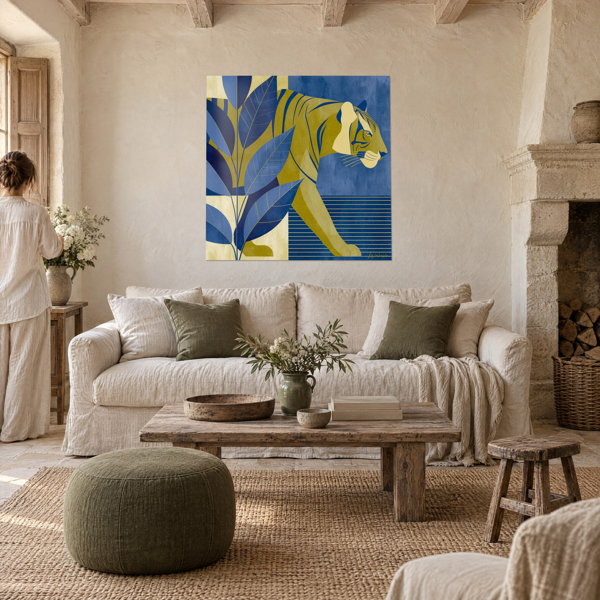 Wall art of an ochre striped tiger-cat walking between navy and cream leaves, seen from behind by a couple above a sofa in a bright living room