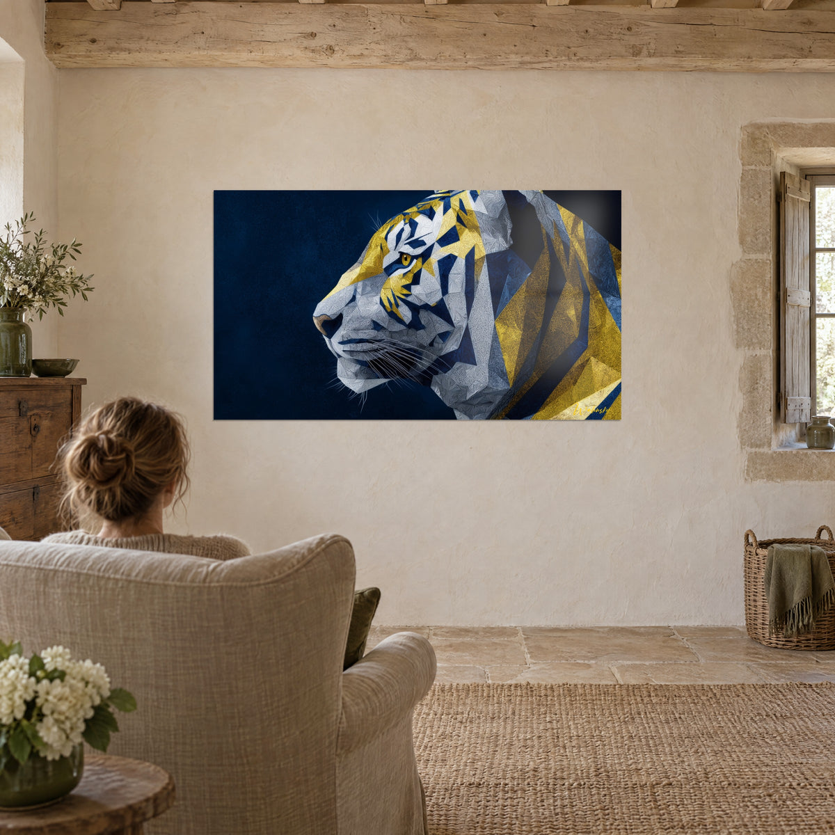 Cuadro Perfil de tigre en facetas plateadas, amarillo azafrán y azul tinta, frente a un sillón de lino en un salón de piedra