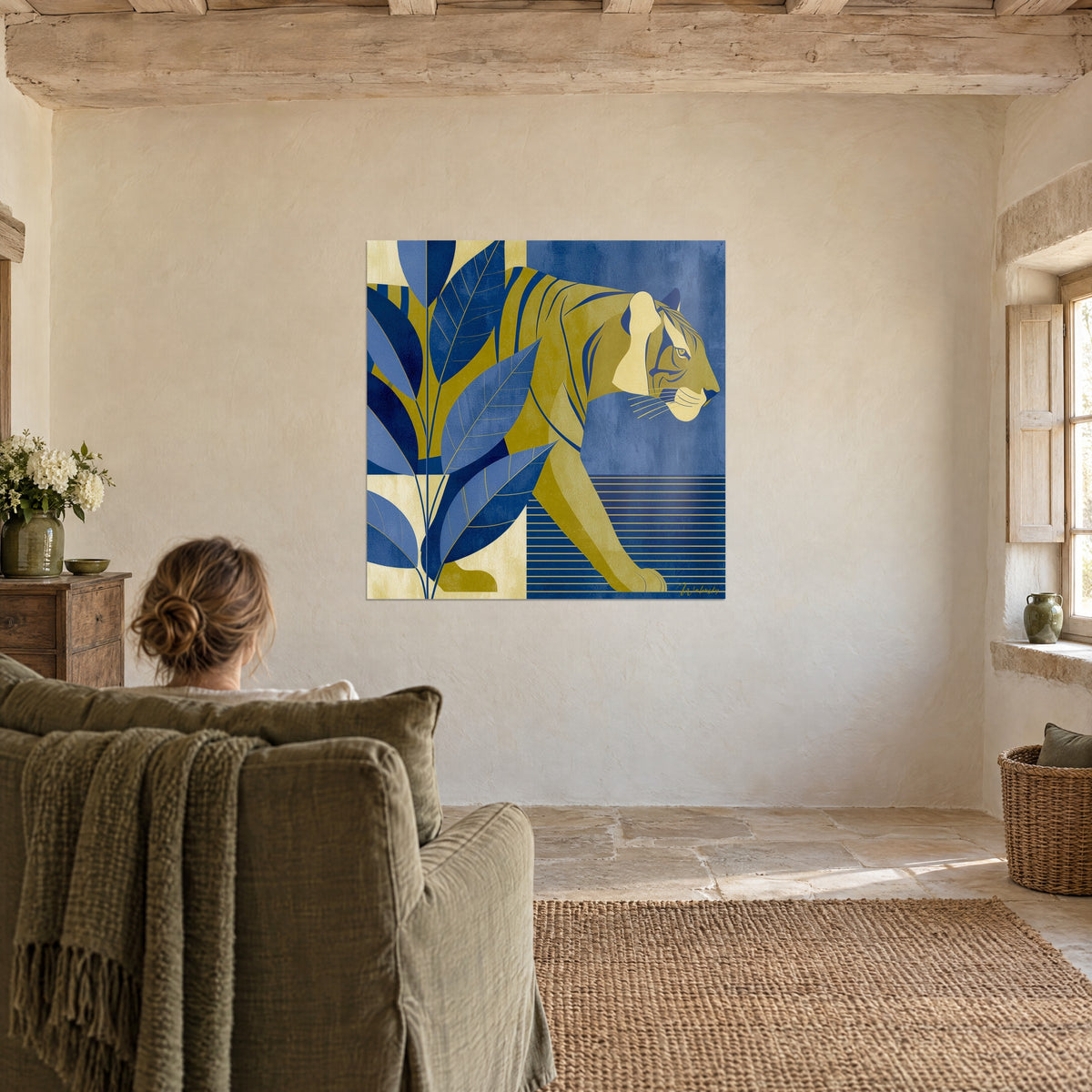 Wall art of a profile feline in ochre and denim blue flat tones, veined leaves, admired by a woman from behind an green armchair