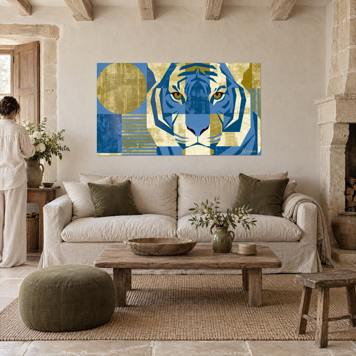 Gemälde mit geometrischem Tiger und bernsteinfarbenen Augen, Kobaltblau und patiniertes Gold, im Vordergrund eine Frau von hinten, über einem Sofa in einem hellen Wohnzimmer