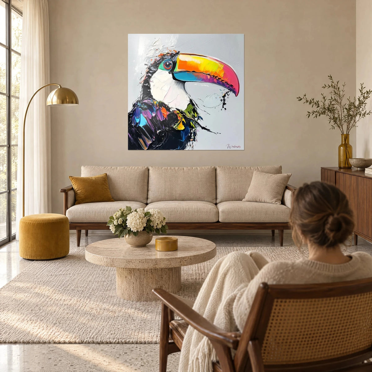 Wall art of an exotic bird with a rainbow beak, black plumage and white throat in thick impasto, above a sofa in a bright living room