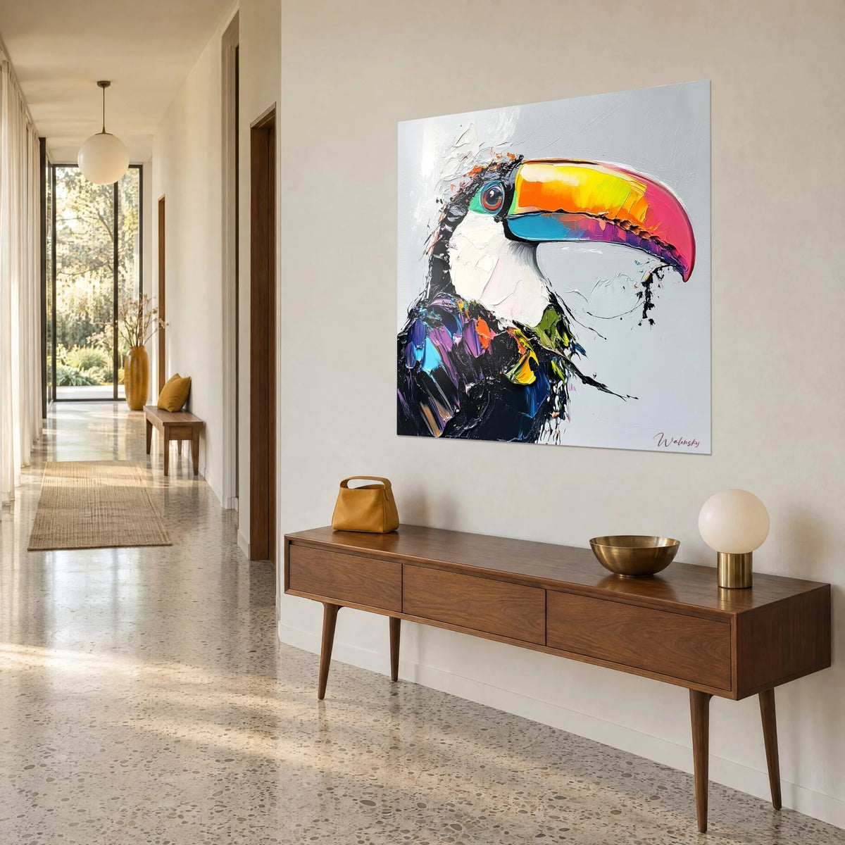 Wall art of a toucan in profile, orange, yellow and pink beak on a pearl grey background, seen three-quarter view, beside a wooden sideboard