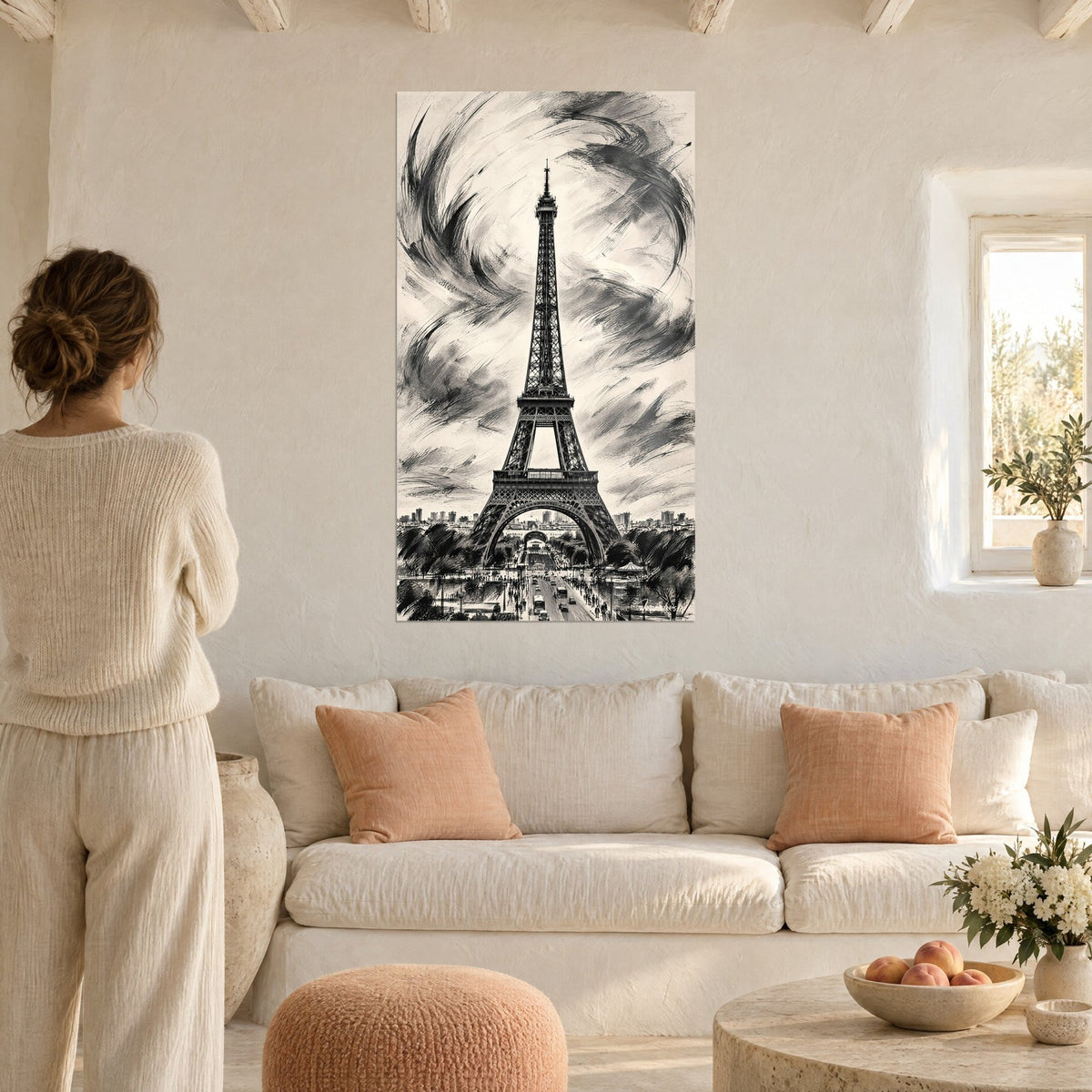 Tableau Tour Eiffel dressée dans un ciel d'encre noire et beige crème, femme de dos, au-dessus d'un canapé dans un salon lumineux