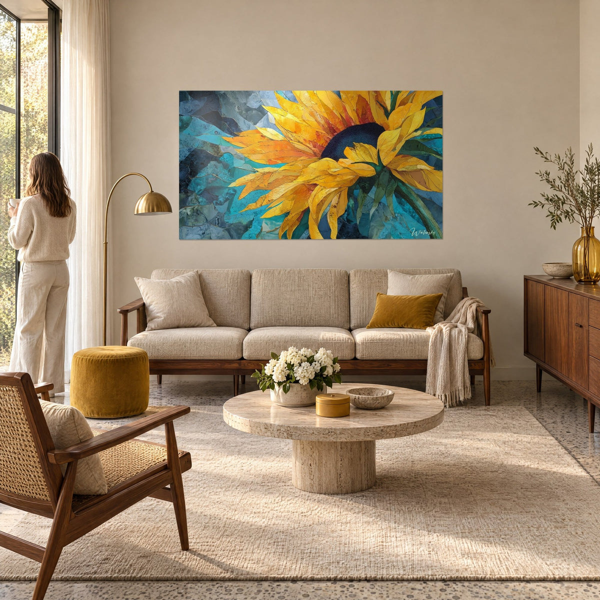 Wall art golden sunflower with amber petals on a turquoise background, a woman seen from behind gazes at it, above a sofa in a bright living room