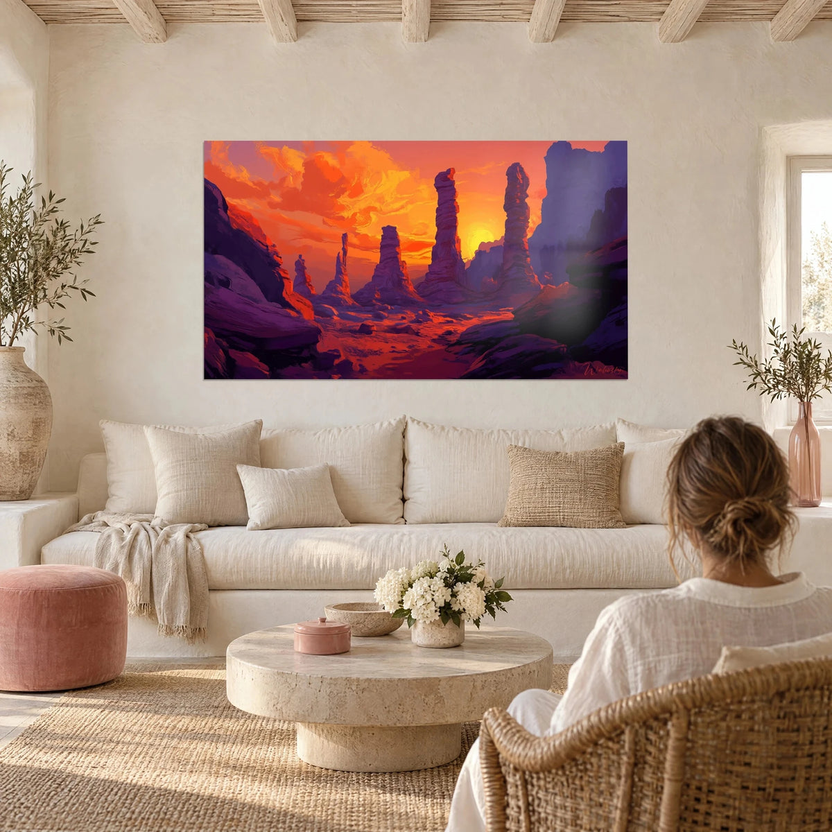 Gemälde mit purpurnen Felstürmen unter einem glühend orangefarbenen Himmel, über einem Sofa in einem hellen Wohnzimmer