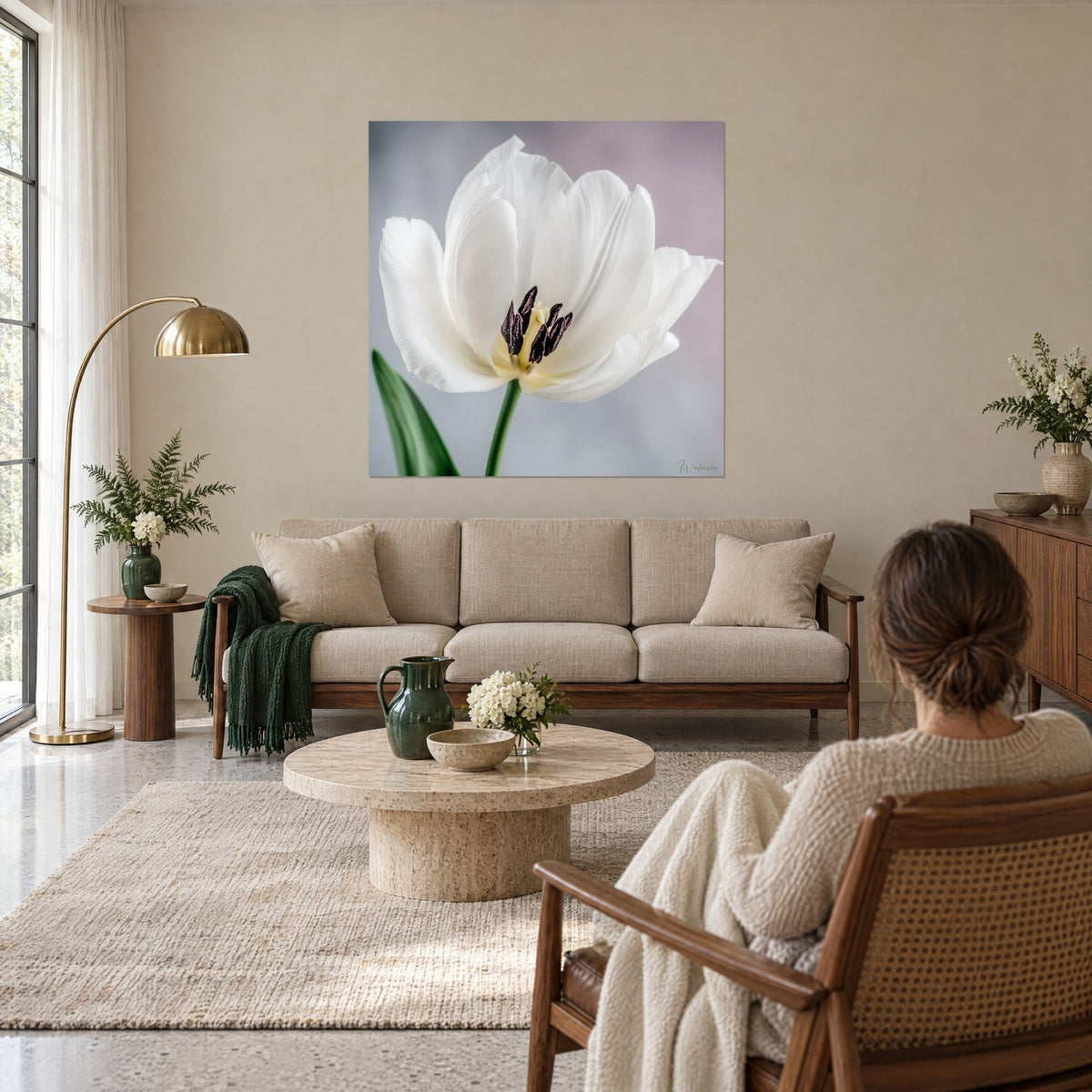 Tableau tulipe immaculée aux étamines pourpres, feuille verte et fond gris-mauve, accroché au-dessus d'un canapé dans un salon lumineux