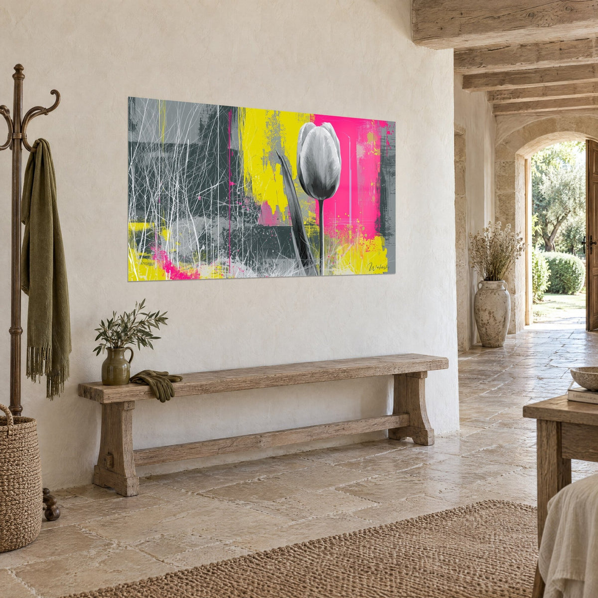 Quadro Fiore monocromatico su stelo nero, colature giallo vivo e rosa acceso, appeso a un muro di pietra di casa di campagna