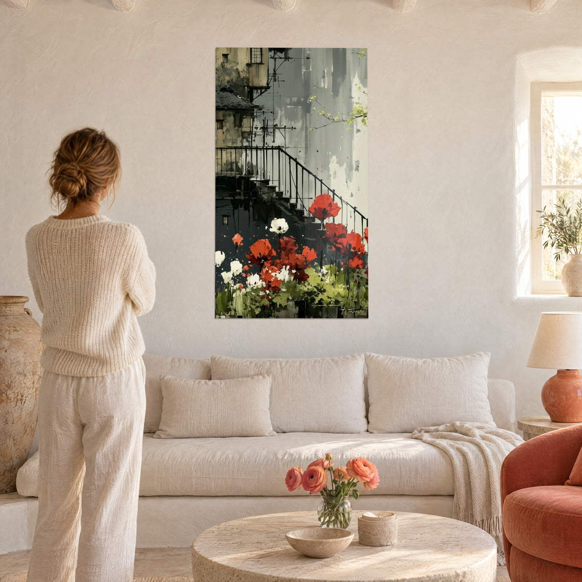 Tableau tulipes écarlates et blanches devant un escalier noir, murs gris, femme de dos, au-dessus d'un canapé dans un salon lumineux