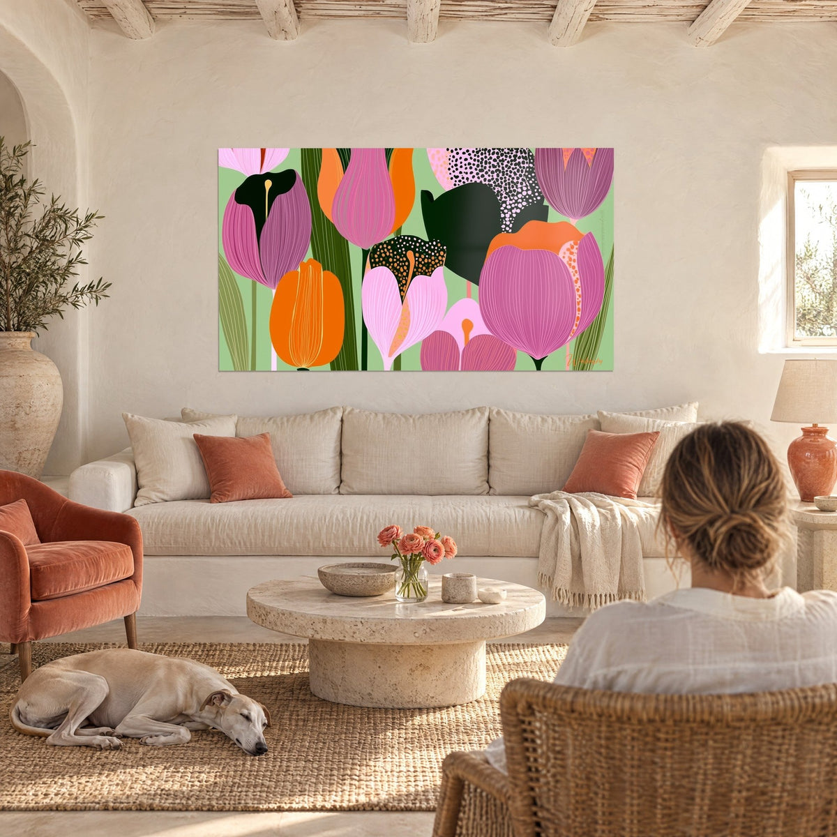 Schilderij met roze en oranje tulpen met gespikkelde bloembladen op een amandelgroene achtergrond, twee personen en een windhond, boven een bank in een lichte woonkamer