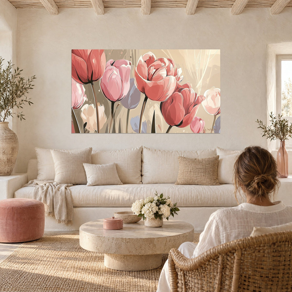 Tableau tulipes rose poudré et corail aux tiges graciles, fond beige, femme de dos, au-dessus d'un canapé dans un salon lumineux