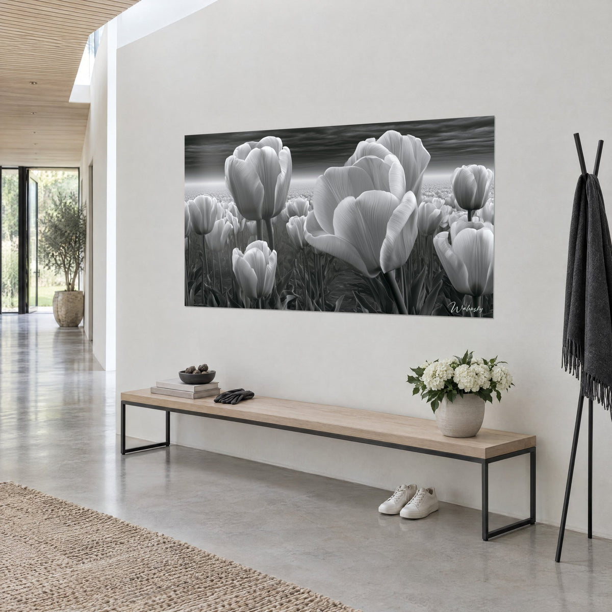 Schilderij grote zilverkleurige bloemen onder een stormachtige antracietkleurige hemel, witte gestreepte bloemblaadjes, aan een crèmekleurige muur in een hal