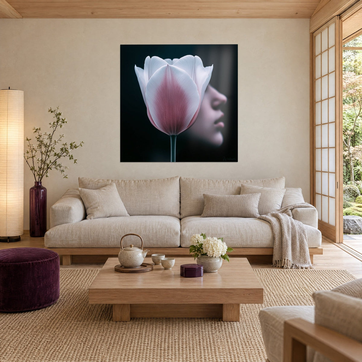 Tableau tulipe blanche au cœur rose poudré, profil de visage flou sur fond noir, au-dessus d'un canapé dans un salon lumineux