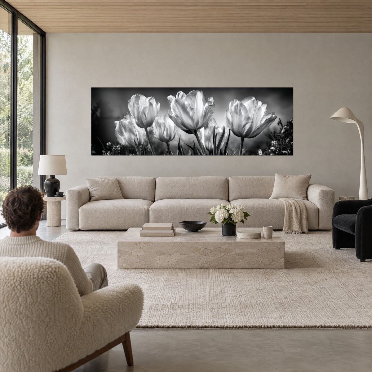 Schilderij witte tulpen van achteren verlicht op zwarte en grijze achtergrond, boven een bank in een lichte woonkamer