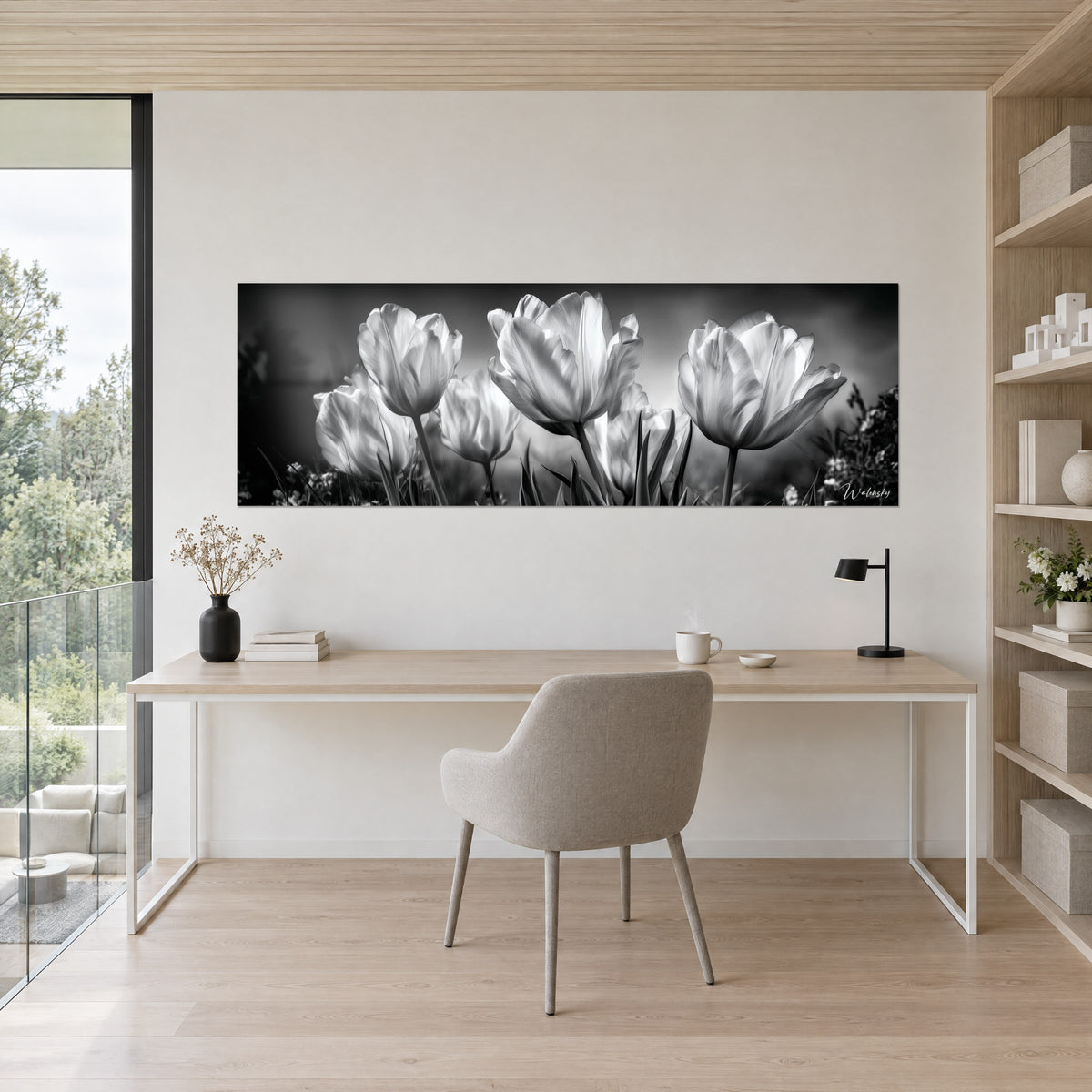 Schilderij parelmoerkleurige kelken en fijne stengels in zwart-wit, crèmekleurige muur boven een bureau van licht hout en een grijze stoel
