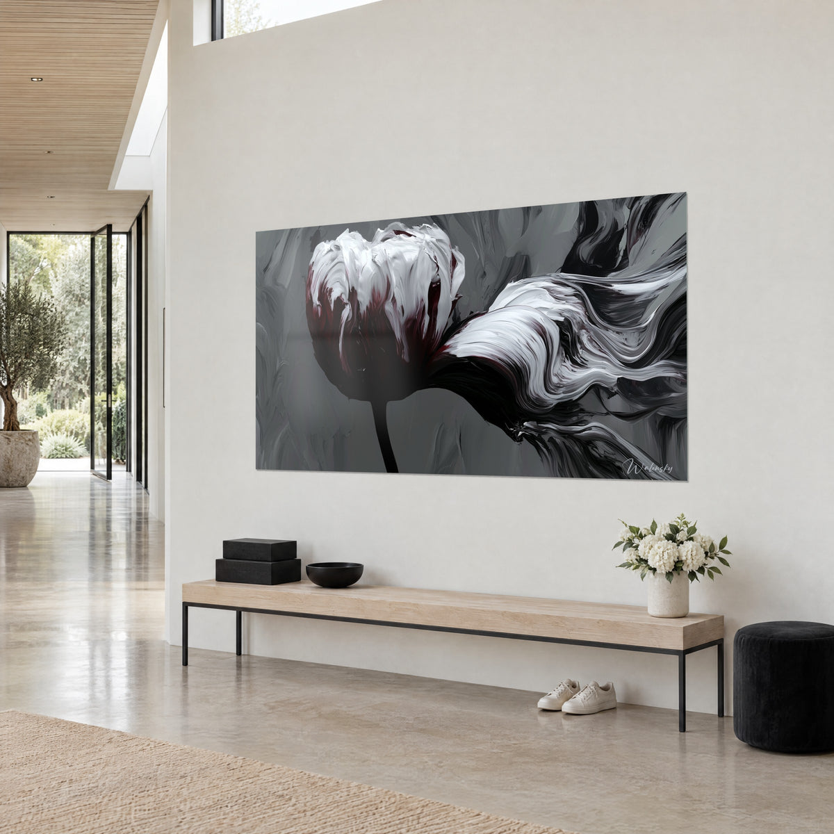 Tableau fleur de peinture empâtée blanche, cœur bordeaux, tige noire et volutes grises, vue de trois-quarts, sur un mur clair près d'un banc en bois