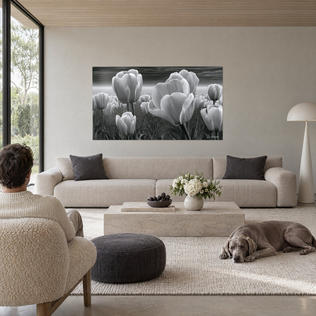 Schilderij tulpenveld in zwart-wit, parelgrijze bloemblaadjes en antracietkleurige lucht, boven een bank in een lichte woonkamer