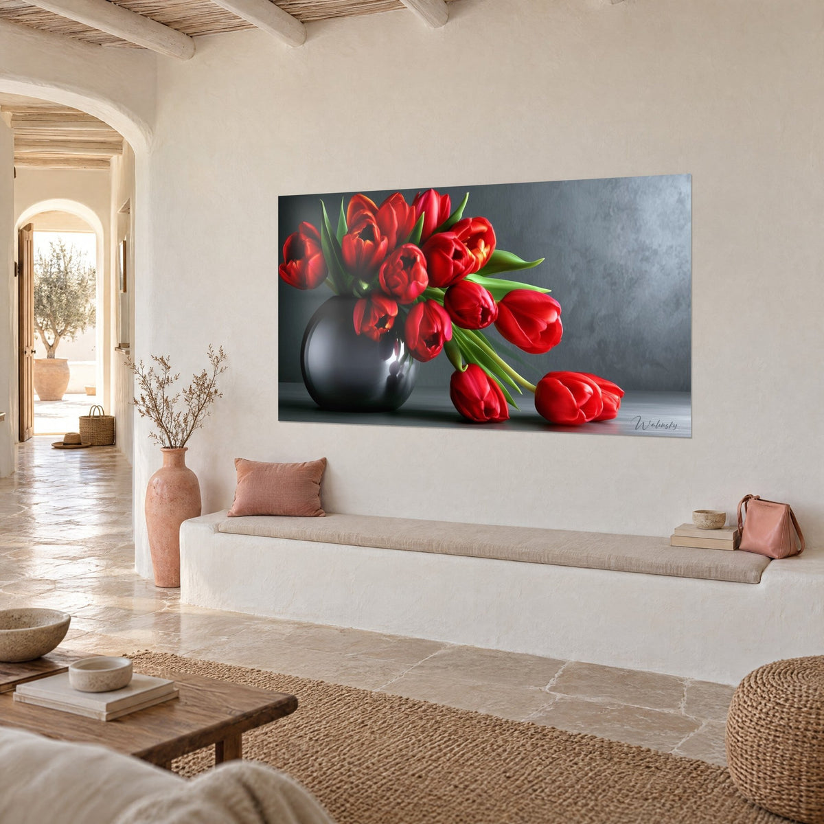 Tableau fleurs rouge vif aux tiges vertes penchées hors d'une boule de verre noire, mur de pierre ocre, banquette blanche et sol dallé