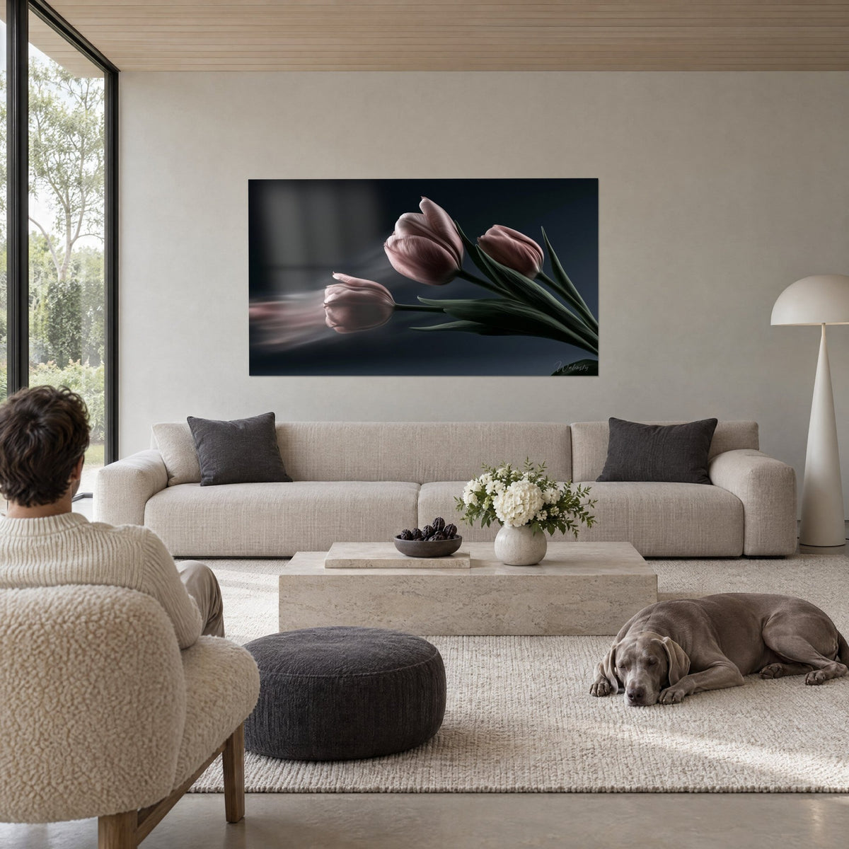 Tableau bouquet de tulipes mauve pâle sur fond ardoise, sillage flou à gauche, deux personnes de dos et un Weimaraner au-dessus d'un canapé dans un salon lumineux