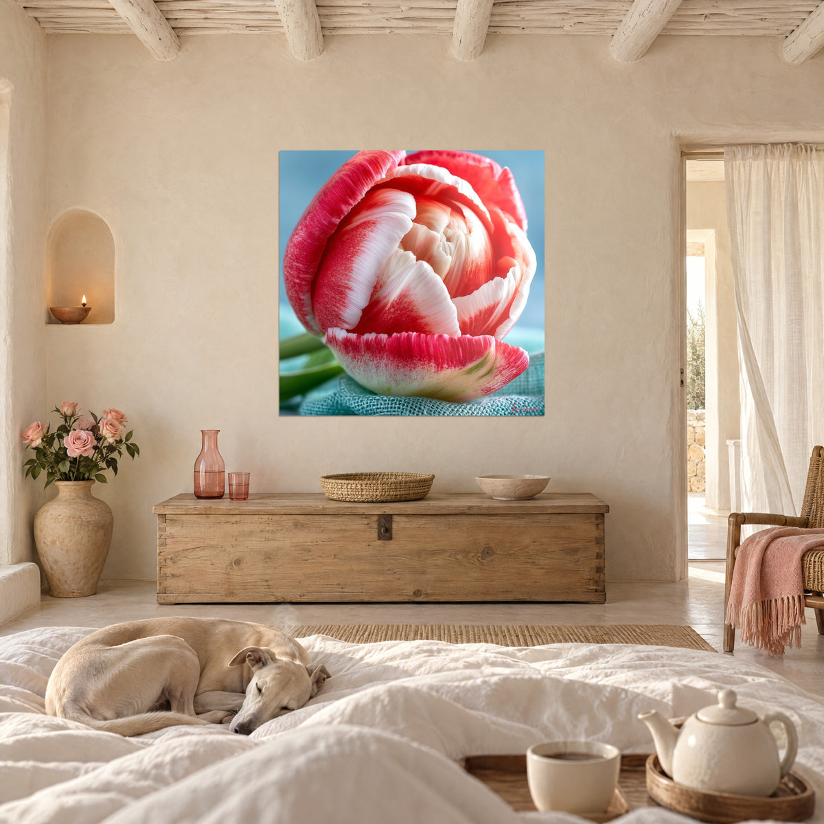 Wall art tulip bloom in a spiral of raspberry pink and cream white on blue-green linen, sleeping greyhound, above a bed in a bright bedroom
