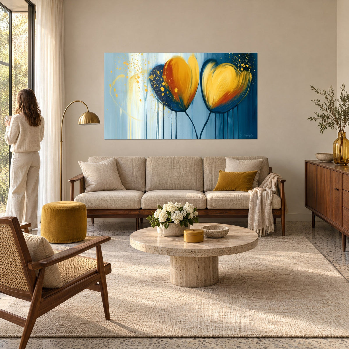 Wall art yellow tulips with saffron and rust petals, dripping navy stems, above a sofa in a bright living room