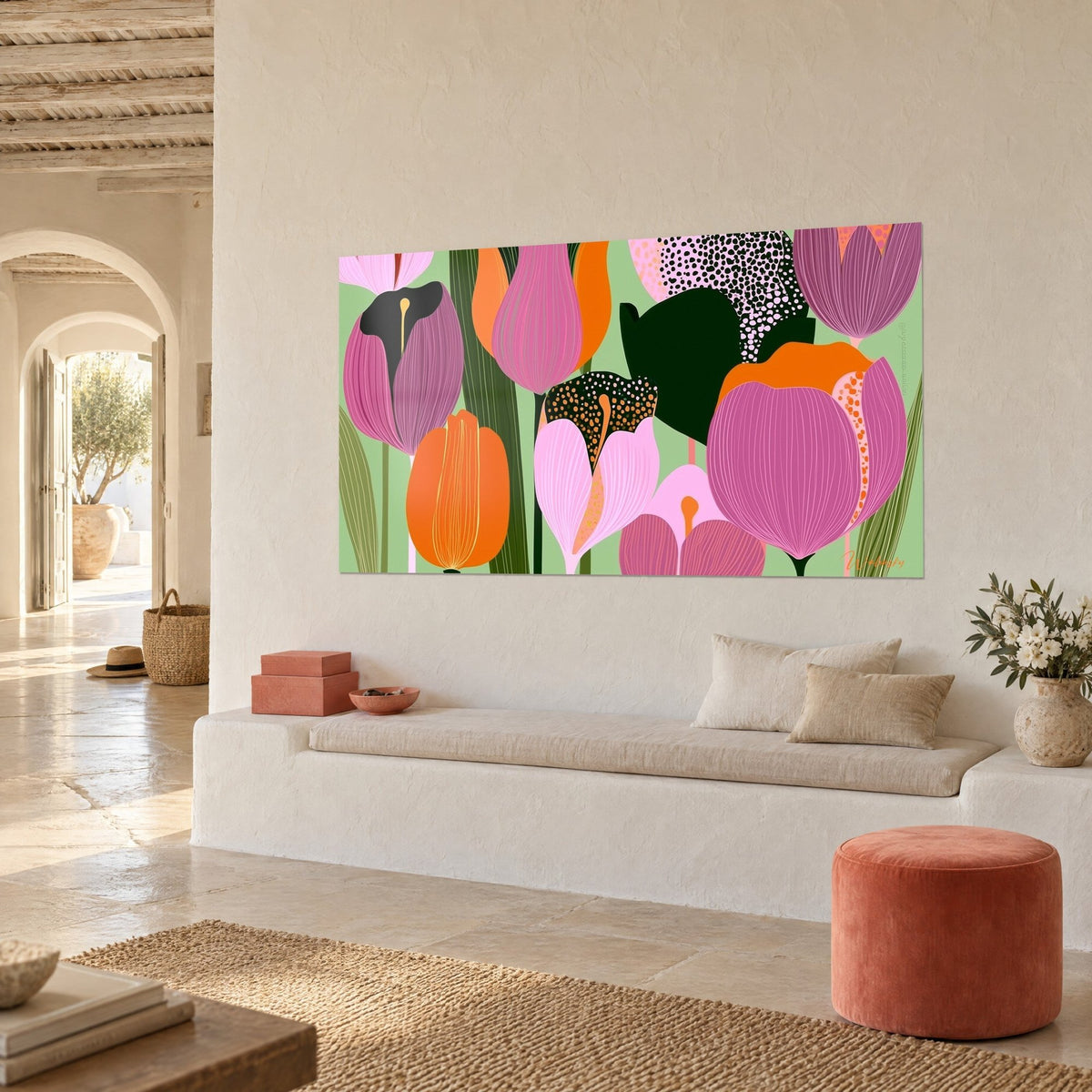 Schilderij met gestileerde magenta en oranje bloemen, olijfgroen gebladerte en zwarte stippen, opgehangen in een woonkamer met lichte stenen muren en een witte bank