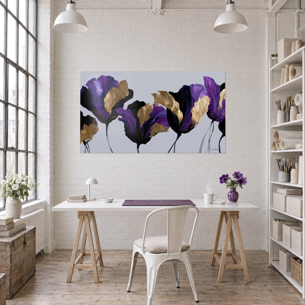 Wall art of aubergine petals and gold leaves, elongated black stems, white wall above a trestle desk in a bright studio