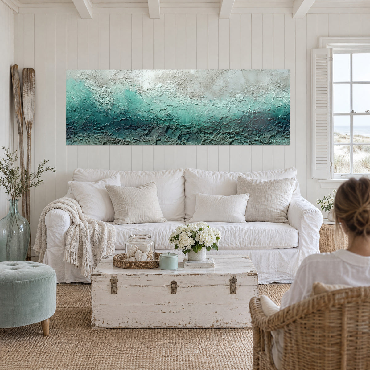 Wall art with mineral relief in turquoise and cream white, thick foamy impasto, two people seen from behind above a sofa in a bright living room