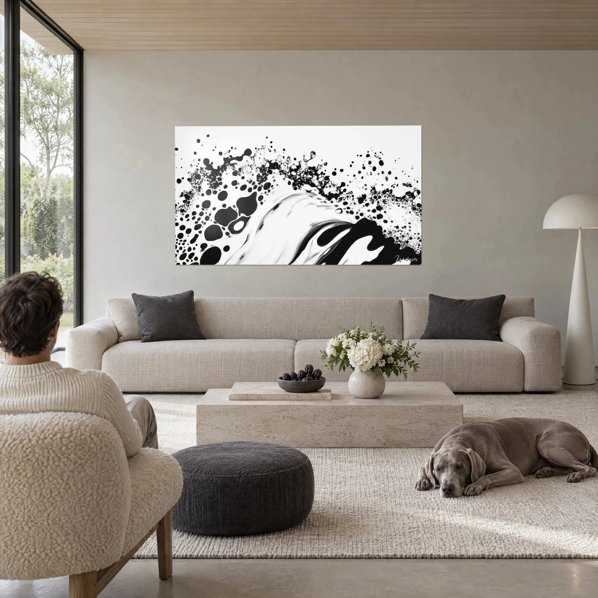 Wall art black ink foam crest splashing across a white background, droplets falling like rain, above a sofa in a bright living room