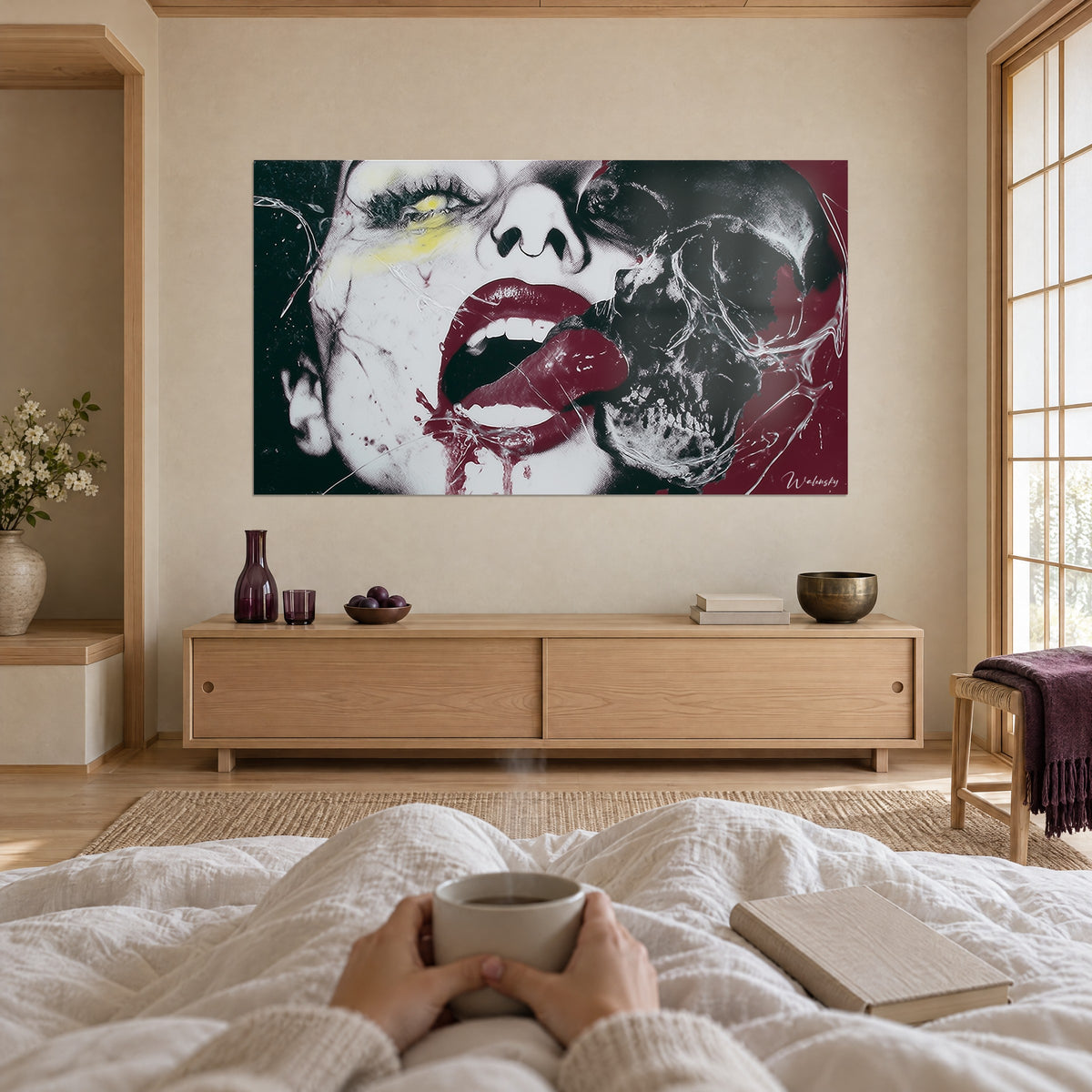 Cuadro de boca entreabierta con dientes blancos y un hilo de sangre oscura, calavera negra sobre fondo burdeos, visto de espaldas, encima de una cama en un dormitorio claro