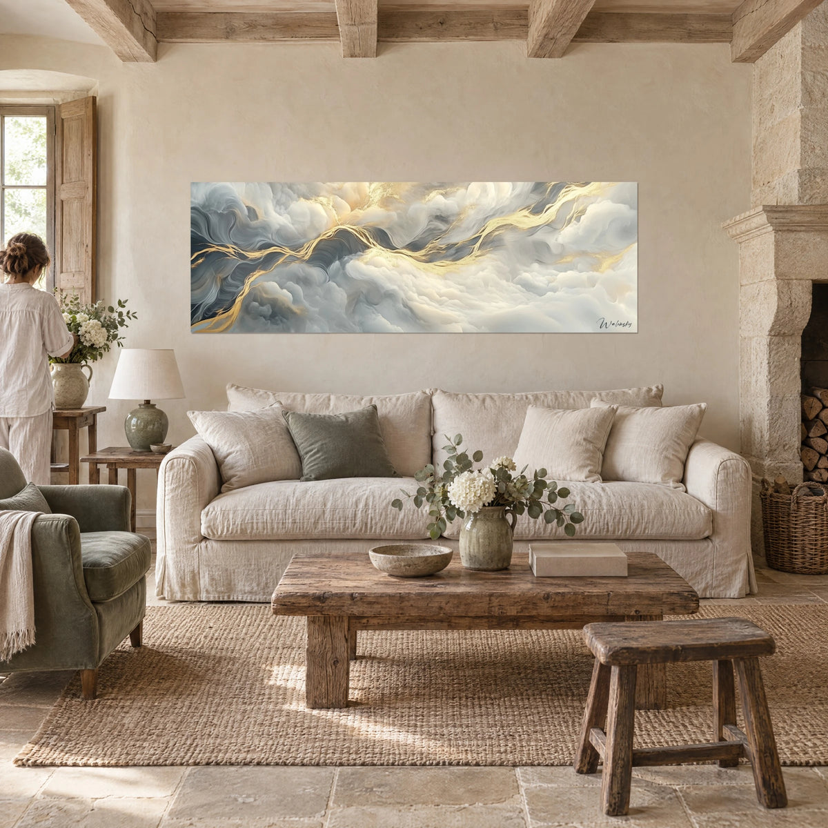 Tableau nuages gris ardoise veinés d'or, panoramique, observé par une femme de dos au-dessus d'un canapé dans un salon lumineux