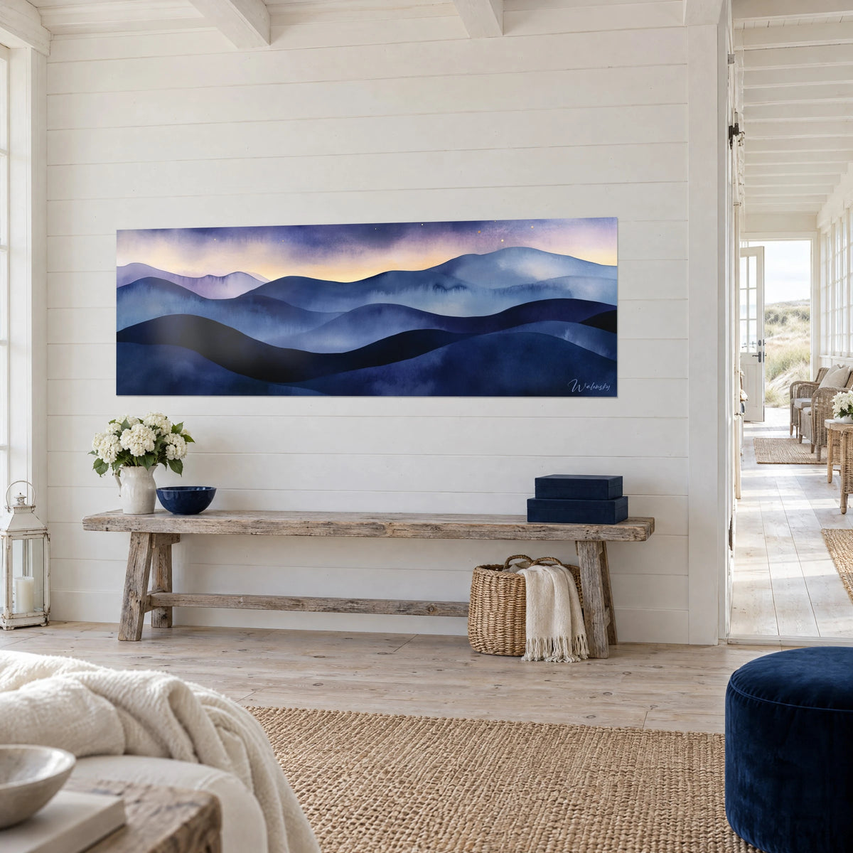 Quadro Creste montuose ondulate in indaco e lilla sotto un cielo ambrato, appeso alla parete in legno bianco di una casa sul mare