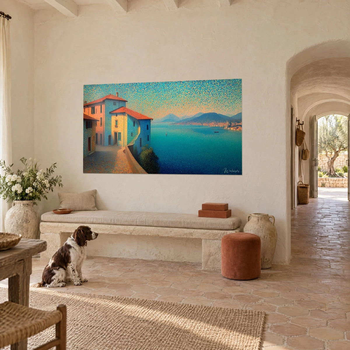 Tableau maisons à toits de tuiles orange dominant un lac azur, points de couleur chatoyants, mur crème, spaniel assis devant