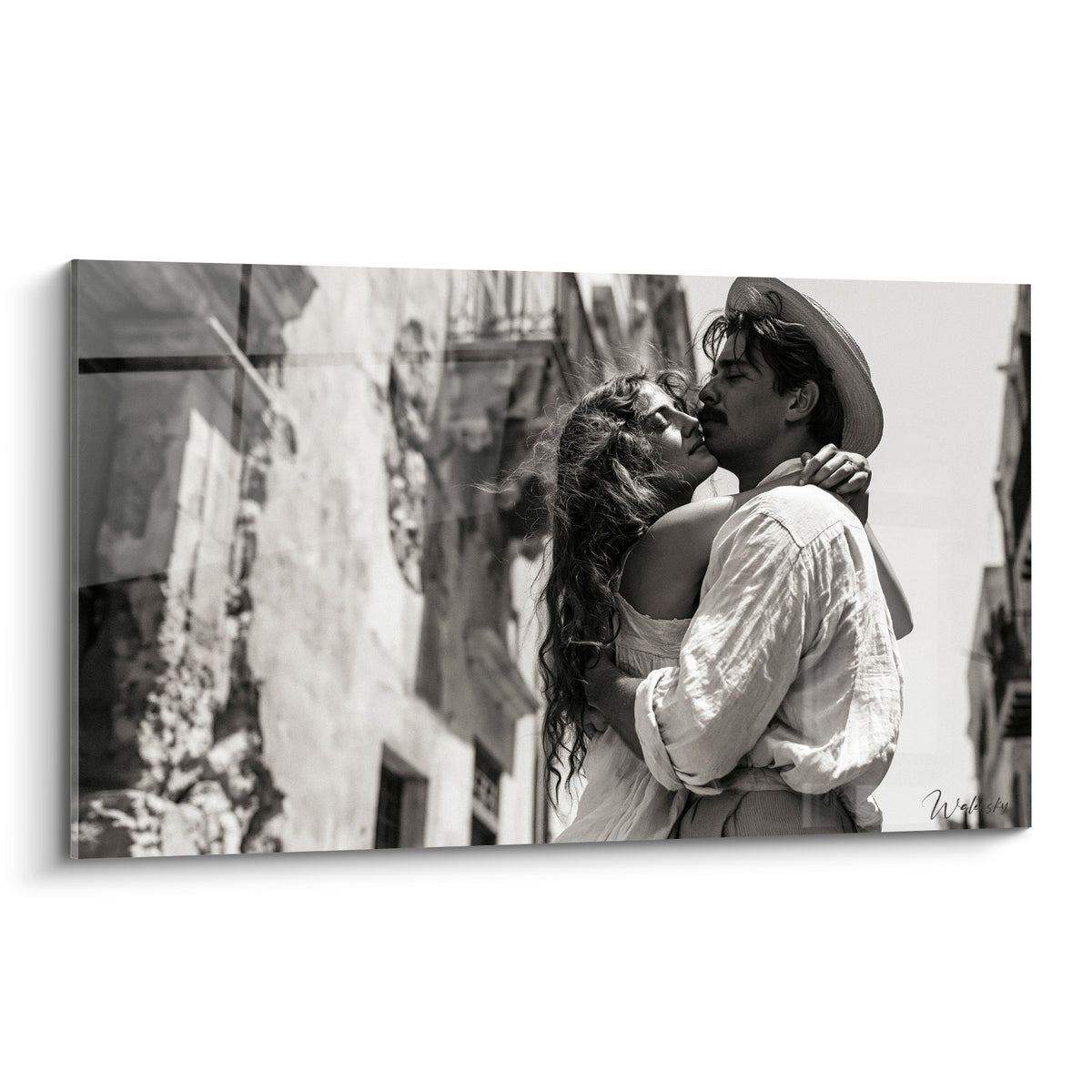 Couple enlacé en noir et blanc, chemise blanche et cheveux bouclés, façade anthracite en fond
