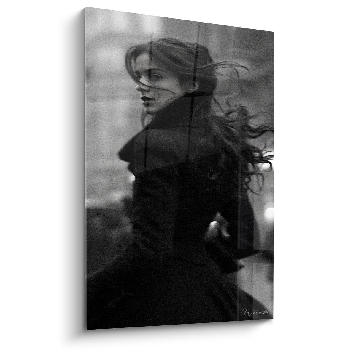 Femme aux cheveux noirs et manteau anthracite se retourne dans un flou urbain nocturne gris et blanc