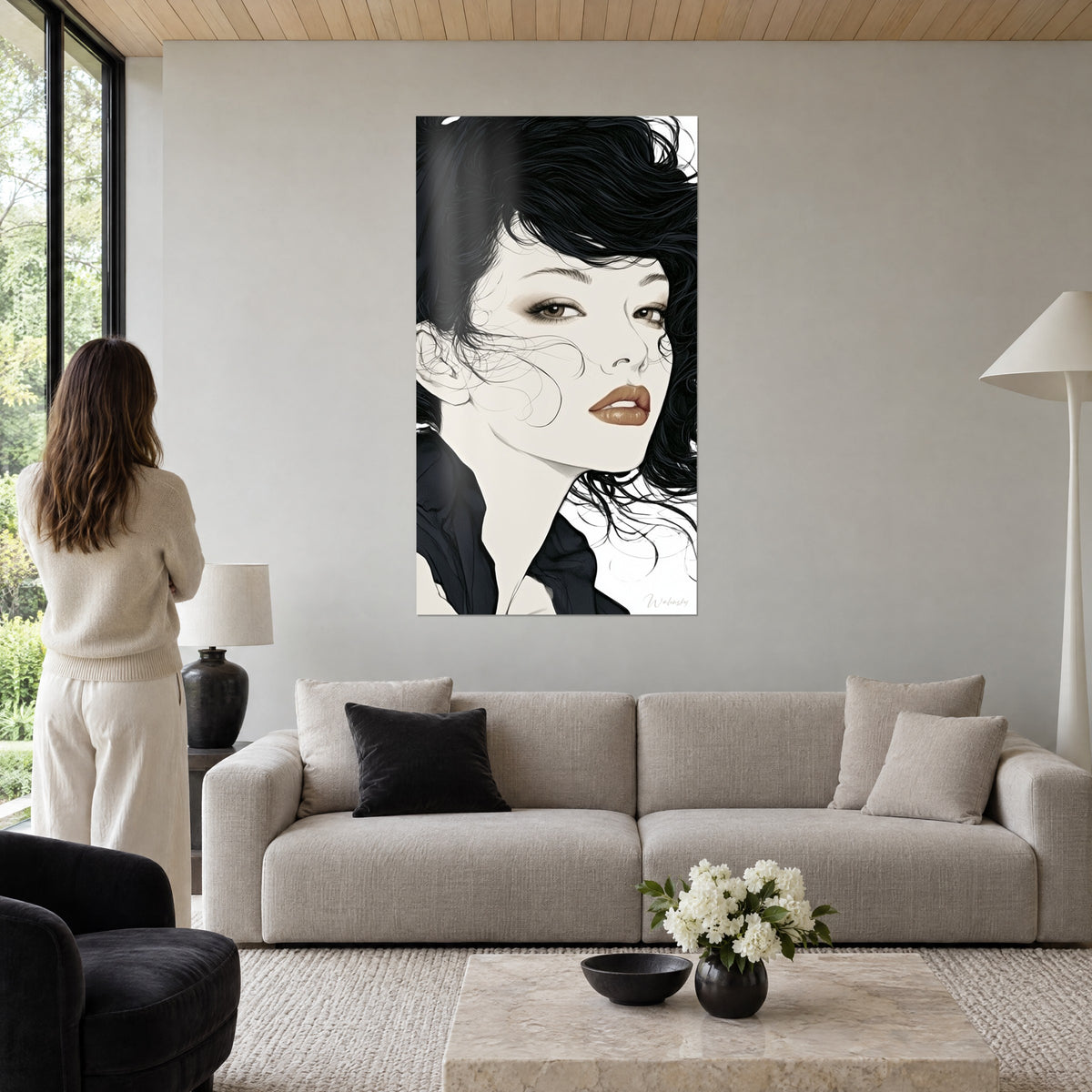 Wall art female portrait in black and ivory, ink-dark curls and copper-toned lips, above a sofa in a bright living room