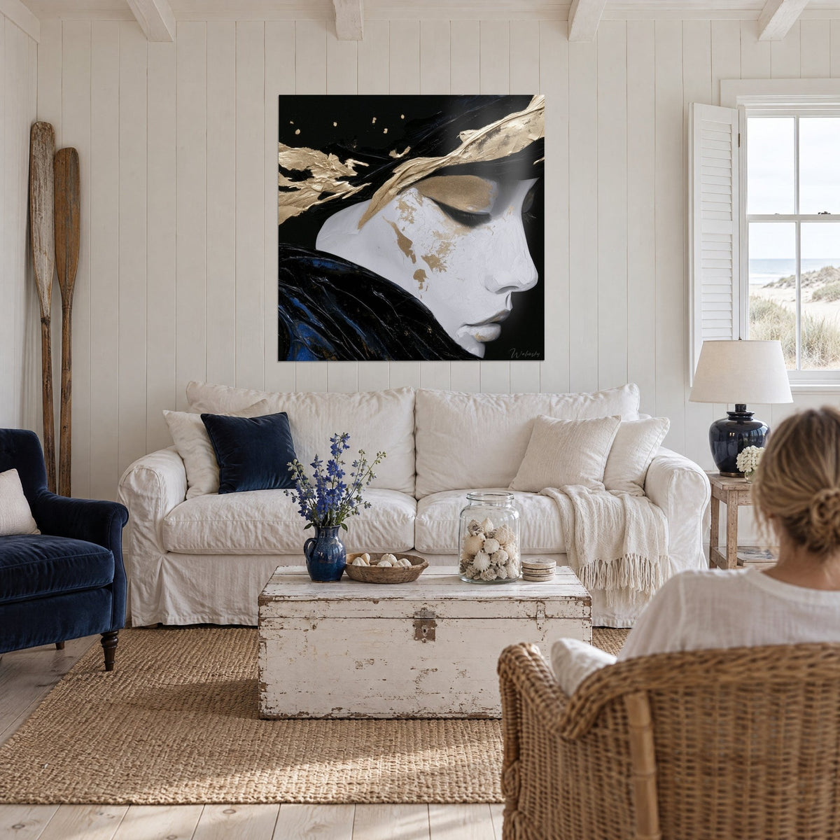 Gemälde Frauenprofil mit geschlossenen Lidern, rissiges Weiß, Gold und Schwarz, über einem Sofa in einem hellen Wohnzimmer