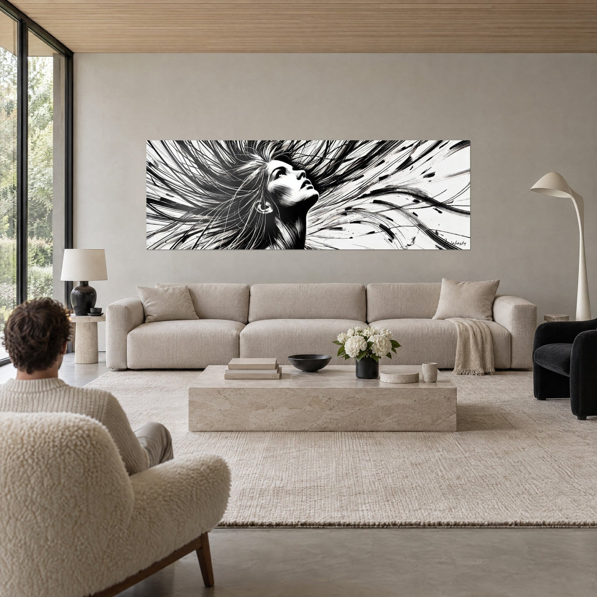 Wall art woman's face lifted toward the sky, black flowing strands of hair on a white background, above a sofa in a bright living room