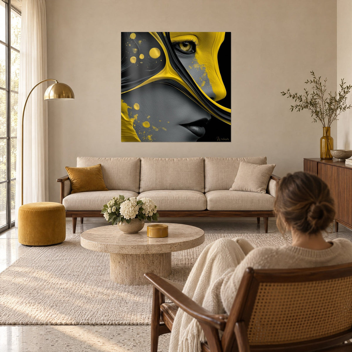 Wall art profile of a face painted in mustard yellow and charcoal grey, golden eye, splashes, above a sofa in a bright living room