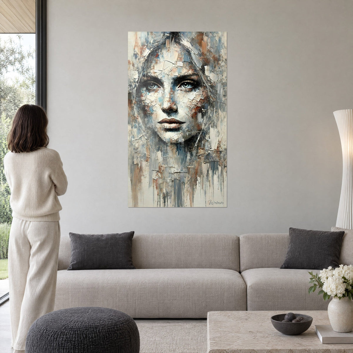 Gemälde fragmentiertes Gesicht mit blaugrauen Augen, ocker- und cremefarbene Splitter, Rückenansicht einer Person, über einem Sofa in einem hellen Wohnzimmer