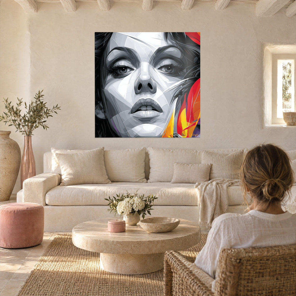 Wall art fractured portrait in grey and white, red and orange feathers, woman seen from behind, above a sofa in a bright living room