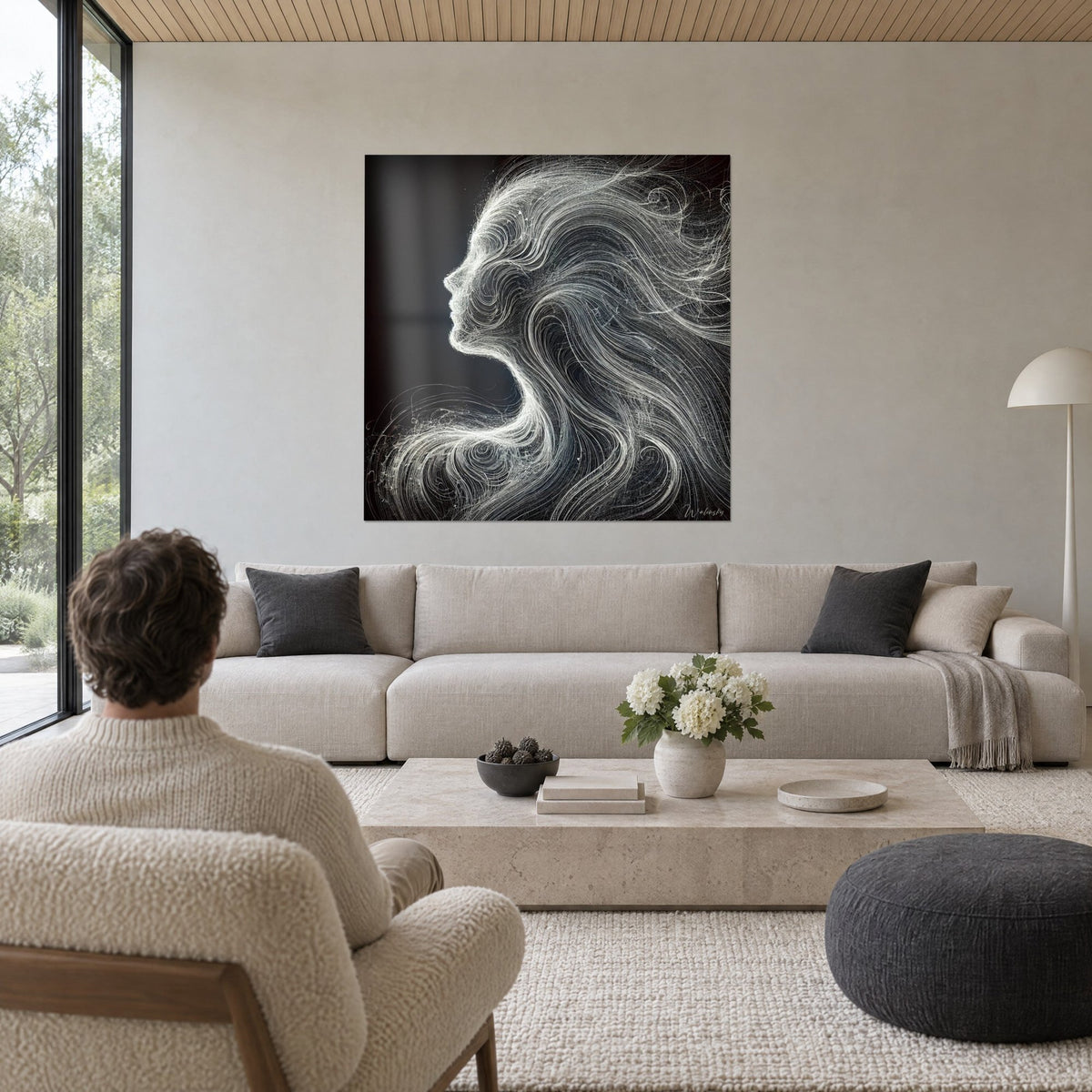 Cuadro perfil femenino con mechas blancas arremolinadas sobre fondo negro, bajo la mirada de un hombre, encima de un sofá en un salón luminoso