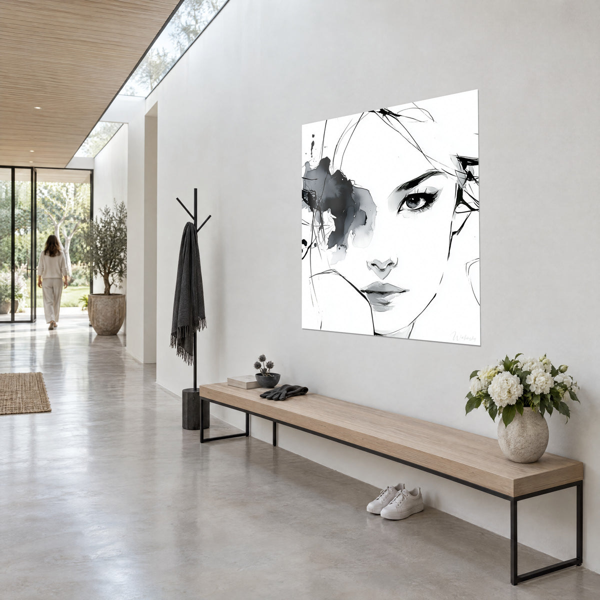 Cuadro rostro de trazo fino y aguada gris, ojo realzado con pestañas negras y labios cerrados, sobre pared blanca junto a un banco largo de madera