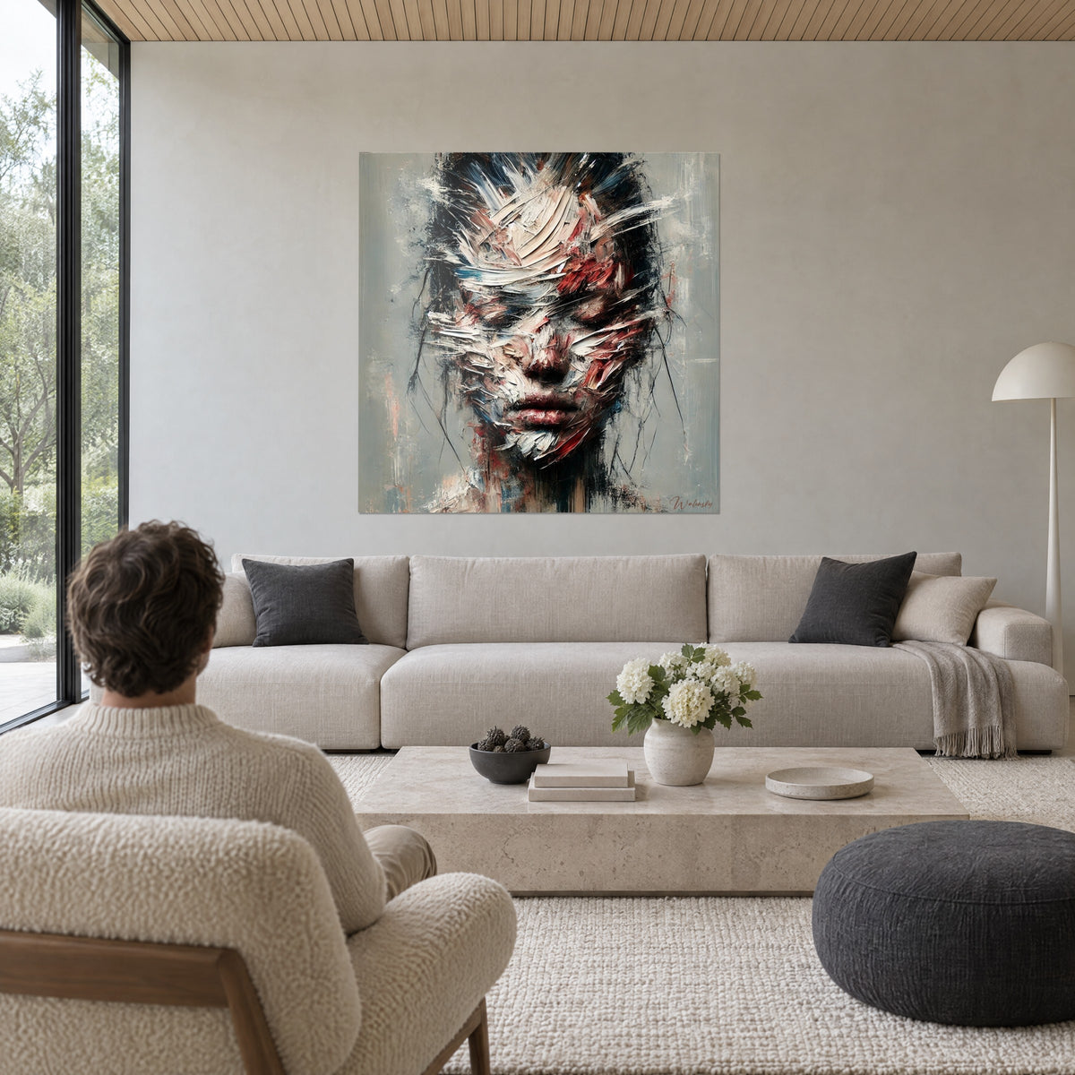 Schilderij gefragmenteerd gezicht met witte en rode paletmesstreken, grijze achtergrond, koppel van achteren, boven een bank in een lichte woonkamer