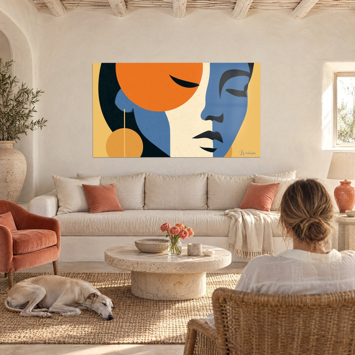 Quadro volto geometrico in blu e arancione, sole tondo e orecchino ocra, sopra un divano in un soggiorno luminoso