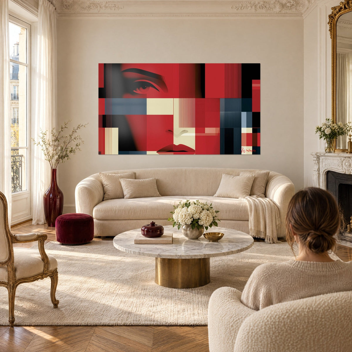 Wall art with a fragmented portrait, a black-lined eye on carmine red and ivory blocks, hanging above a sofa in a bright living room